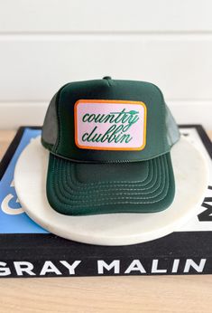 Country Clubbin' Trucker Hat, forest green trucker hat with orange and pink patch in the center of the hat with forest green embroidered text country clubbin