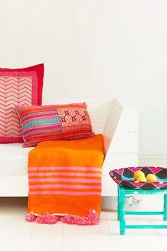 a white couch with colorful pillows on it and a small table in front of it