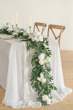 the table is set with white flowers and greenery, along with candles on it