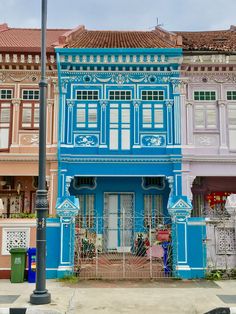 an old building painted blue and pink in front of other buildings on a street corner