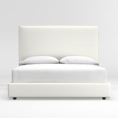 a bed with white sheets and pillows on it's headboard, in front of a gray background