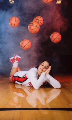 a woman laying on the floor in front of basketballs