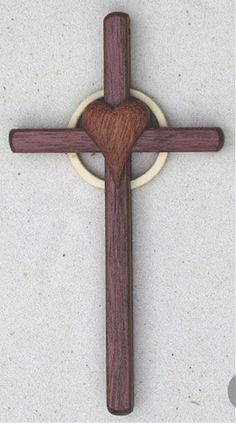 a wooden cross with a heart in the center on a white surface, surrounded by two circles