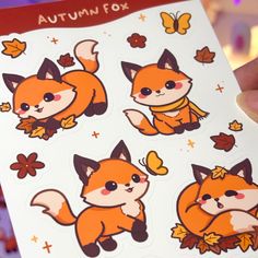 a person holding up an autumn fox sticker