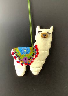 a ceramic llama ornament hanging from a green string on a black surface