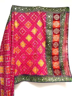 This is an eye catching mirror work silk dupatta with bandhaj work throughout. Bandhaj is a tie dye technique traditionally used in Rajasthan, India, used across multiple items of clothing.  The delicate gold threads are shown in traditional patterns throughout and are perfect for a mendi or pre wedding party to add that colour and sparkle to any simple outfit.  Need a matching suit to go with? Just email info@sagrahi.co.uk for more information.  In stock ready to dispatch and available in other Silk Traditional Wear With Gota Work, Red Silk Dupatta With Mirror Work, Pink Semi-stitched Traditional Wear For Festival, Pink Silk Choli With Mirror Work, Pink Silk Dupatta With Gota Work, Bohemian Silk Salwar Kameez With Mirror Work, Pink Dupatta With Dori Work For Traditional Ceremonies, Multicolor Silk Traditional Wear With Mirror Work, Silk Multicolor Salwar Kameez With Mirror Work