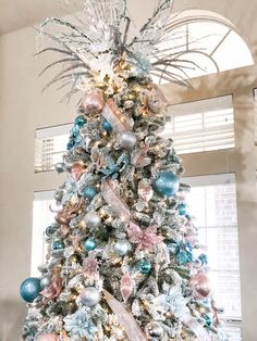 a decorated christmas tree with blue, pink and silver ornaments in the shape of pineapples