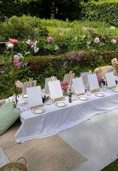 an outdoor table set up with place settings and easels on it for art work