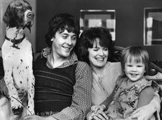 an old black and white photo of two women and a child with a dog on their lap