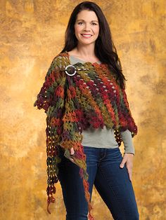 a woman standing in front of a wall wearing a knitted shawl