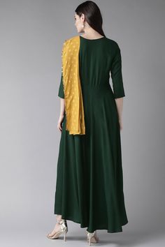 This ahalyaa poly rayon a line kurta in green is ideal to wear on a light festive occasion. The kurta has an attached mustard dupatta. There is no lining in the kurta. Note: height of the model is 5'8" and she is wearing a size 's' from the ahalyaa size chart. Please choose a garment size at least 2" more than your body measurement for ease of wearing and taking off the garment. Product Features:   Color: Dark Green Fabric: Rayon Pattern: Printed Fit: Regular Sleeve: Three-Quarter Sleeves Neck T Green Floor-length Kurta With Dori Work, Emerald Green Kurta Woman, Bottle Green Kurti, Dark Green Kurta Woman, Yellow Anarkali Dress, Fitted Maxi Length Green Kurta, Dark Green Gown, Cotton Anarkali Kurta, Floral Anarkali