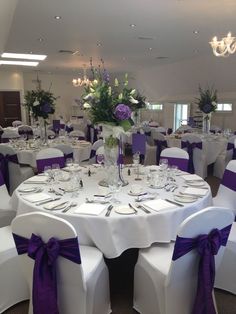 the tables are set with white linens and purple sashes