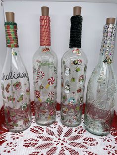 three glass bottles with candy canes and candies on them sitting on a table