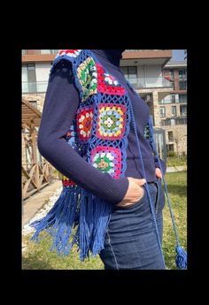 a woman wearing a crocheted sweater and holding a blue purse in her hands