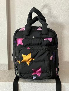 "Children's quilted black bagpack Gold, purple, blue and silver neon stars Soft Handle and adjustable back straps ZIpper closure 2 inside pockets big enought to hold an iphone and snack Key chain outside Condition is great Dimension - height 13\" length 10\" depth 5\" handle 6\"" Black Quilted School Bag, Black Quilted Backpack, Black Quilted Standard Backpack, Neon Stars, Quilted Cushion, Backpack Cute, Black Children, Childrens Backpacks, Black Quilt