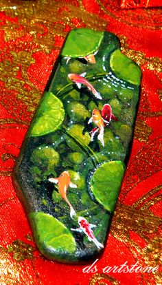 a green and red vase sitting on top of a table covered in water lilies