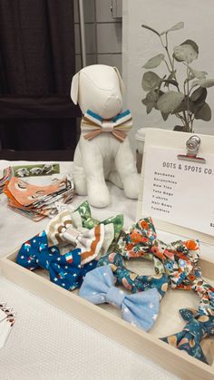 an assortment of bow ties on display in a wooden box next to a stuffed animal