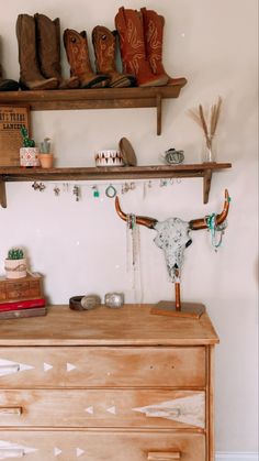 a wooden dresser topped with lots of cowboy boots and other items on top of it