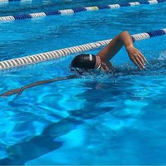 a woman swimming in a pool with her hand on the water's edge