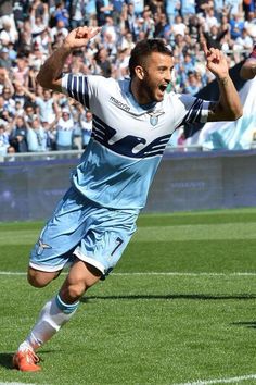 a soccer player running on the field with his arms in the air as he celebrates