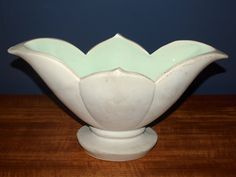 a white vase sitting on top of a wooden table