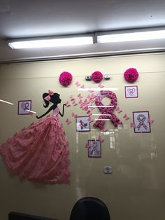 a display case with pink decorations and pictures on the wall, including a woman's dress