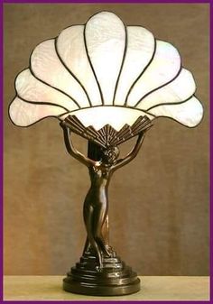 a table lamp with a woman holding a fan on it's head and arms