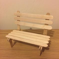 a small wooden bench sitting on top of a wooden table next to a white wall