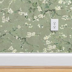 an electrical outlet in front of a wallpapered background with white and green flowers