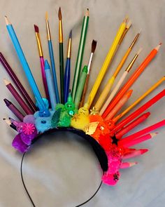 an assortment of paintbrushes arranged in a rainbow - hued headdress