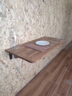 a wooden table with a plate on it in front of a wall made of plywood