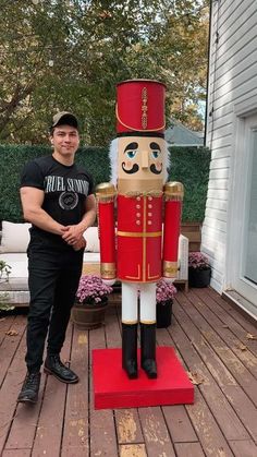 a man standing next to a large wooden nutcracker