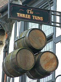 there are three barrels hanging from the side of this building that says the three tuns