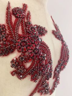 a red beaded necklace on a mannequin's torso with beads and leaves