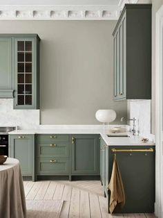 a kitchen with green cabinets and white counter tops, along with a round dining table