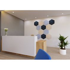 an office with white walls and blue chairs in front of the reception desk, which has hexagonal tiles on the wall