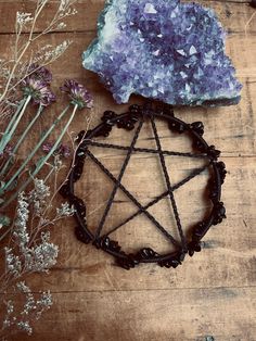 a wicker wheel, crystals and flowers on a wooden table next to a rock