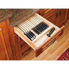 an open drawer in the middle of a kitchen with utensils and knives on it