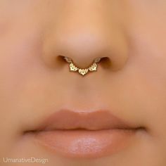 a woman's nose with a gold nose ring in the shape of an occupant