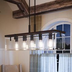 a chandelier hanging from the ceiling in a dining room next to a window