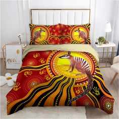 a bed covered in a red and yellow comforter with an animal on it's side