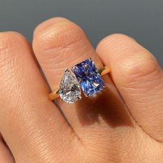 a woman's hand holding an engagement ring with two pear shaped diamonds