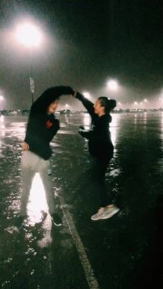 two people are playing in the rain at night