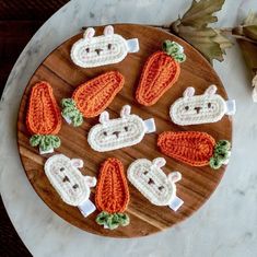 crocheted carrots and bunnies are arranged on a wooden platter with leaves