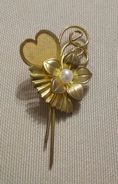 Beautiful vintage Flower brooch, in faux gold, with faux pearl This is such a lovely ittle decorative floral and heart brooch. Measuring 2.5 inches (6 cms) long and1.25 inches (3 cms)wide it has a lovely flower design with a nestling faux pearl, and with a romantic mesh heart. It is in excellent vintage condition. Presented in an Organza gift bag. Please let me know if you have any questions. Thanks for stopping by. Gold Costume Jewelry Pins For Wedding, Flower Shaped Costume Jewelry Brooches For Wedding, Retro Gold Brooch For Anniversary, Vintage Yellow Gold Brooches For Party, Vintage Gold Flower Brooches, Vintage Gold Flower Brooch, Vintage Gold Pins For Anniversary, Vintage Lapel Pin Brooch For Anniversary, Gold Flower Pins For Wedding