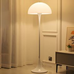 a white lamp sitting on top of a table next to a window