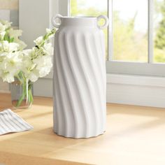 a white vase sitting on top of a wooden table