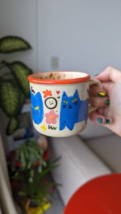 a person holding a cup with cats painted on it