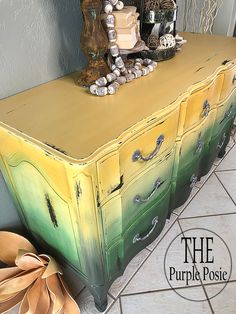 an old dresser is painted yellow and green