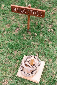 a ring tosser sitting on top of a wooden block in the grass next to a sign that says ring toss